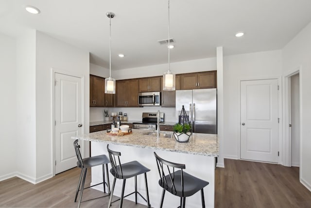 kitchen with a sink, baseboards, visible vents, wood finished floors, and appliances with stainless steel finishes