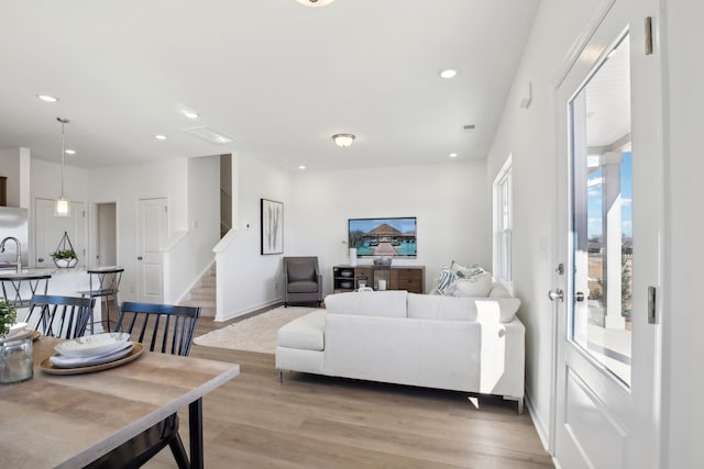 living room with light wood-type flooring, recessed lighting, and stairs