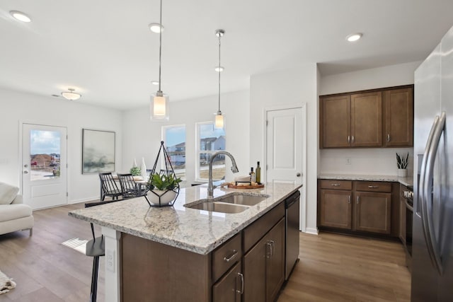 kitchen featuring stainless steel appliances, wood finished floors, a sink, and a breakfast bar area