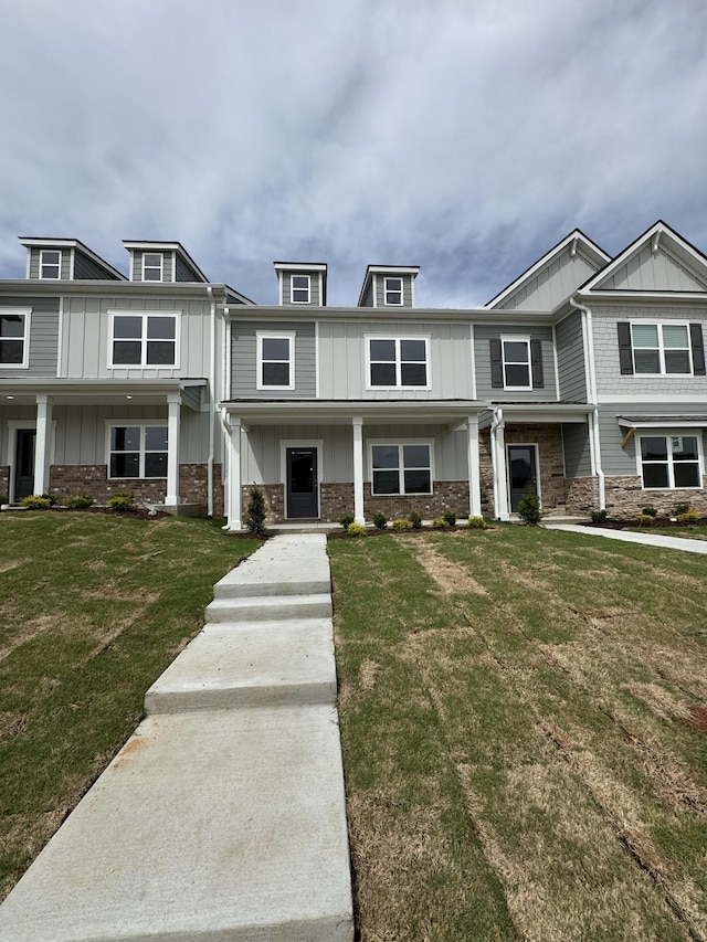 multi unit property with stone siding, a front yard, and board and batten siding