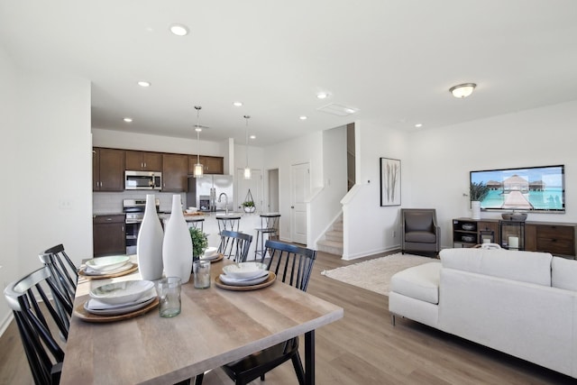 dining room with light wood-type flooring, baseboards, recessed lighting, and stairway