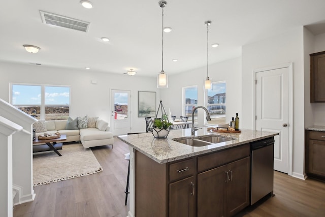 kitchen featuring stainless steel dishwasher, a sink, dark brown cabinets, visible vents, and wood finished floors