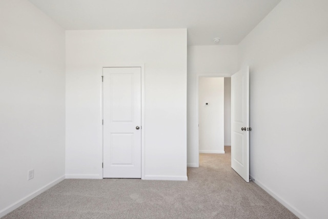 unfurnished bedroom featuring light colored carpet and baseboards