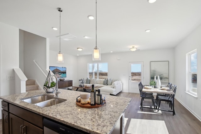 kitchen featuring dark brown cabinets, dishwasher, a sink, light wood-style floors, and decorative light fixtures