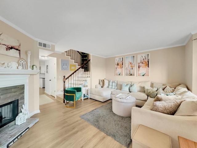 living area with visible vents, wood finished floors, ornamental molding, and stairway