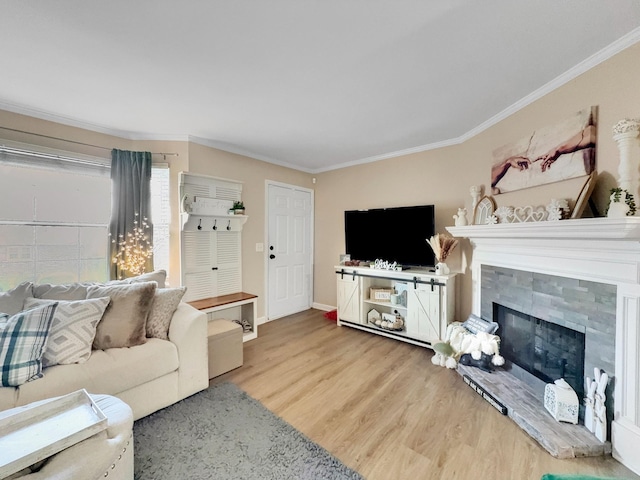 living room with a fireplace with raised hearth, crown molding, baseboards, and wood finished floors