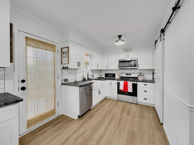 kitchen featuring light wood-style flooring, backsplash, white cabinets, and stainless steel appliances