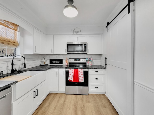 kitchen with white cabinetry, crown molding, backsplash, and stainless steel appliances