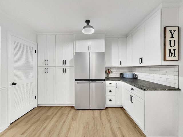 kitchen featuring decorative backsplash, light wood finished floors, white cabinetry, and freestanding refrigerator