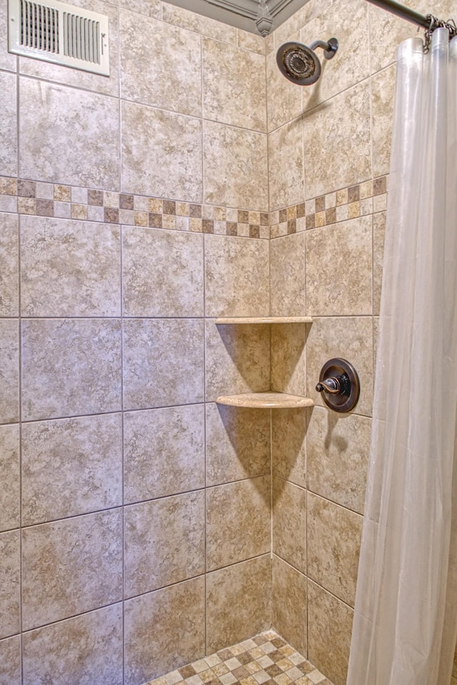 full bathroom featuring a tile shower and visible vents