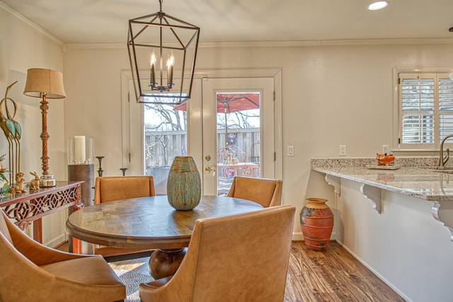 dining space with a notable chandelier, ornamental molding, baseboards, and wood finished floors