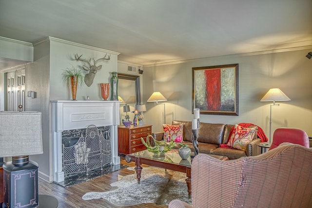 living room featuring crown molding, a fireplace with flush hearth, and wood finished floors