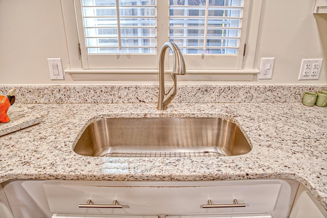 details with a sink and light stone countertops