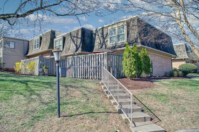 view of home's exterior with a lawn, mansard roof, stairway, a shingled roof, and brick siding