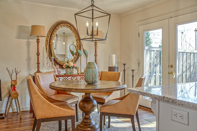 dining area featuring baseboards, a notable chandelier, wood finished floors, and crown molding