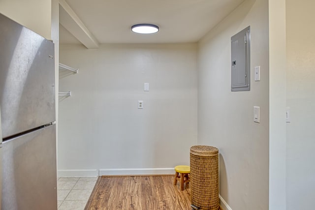 washroom featuring electric panel, baseboards, and light wood finished floors