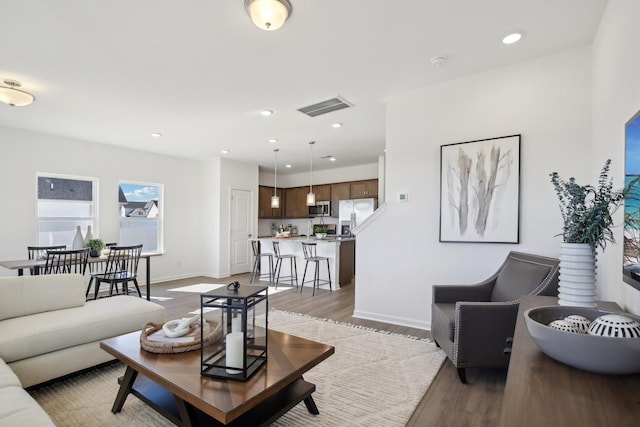 living area featuring recessed lighting, light wood-style floors, visible vents, and baseboards