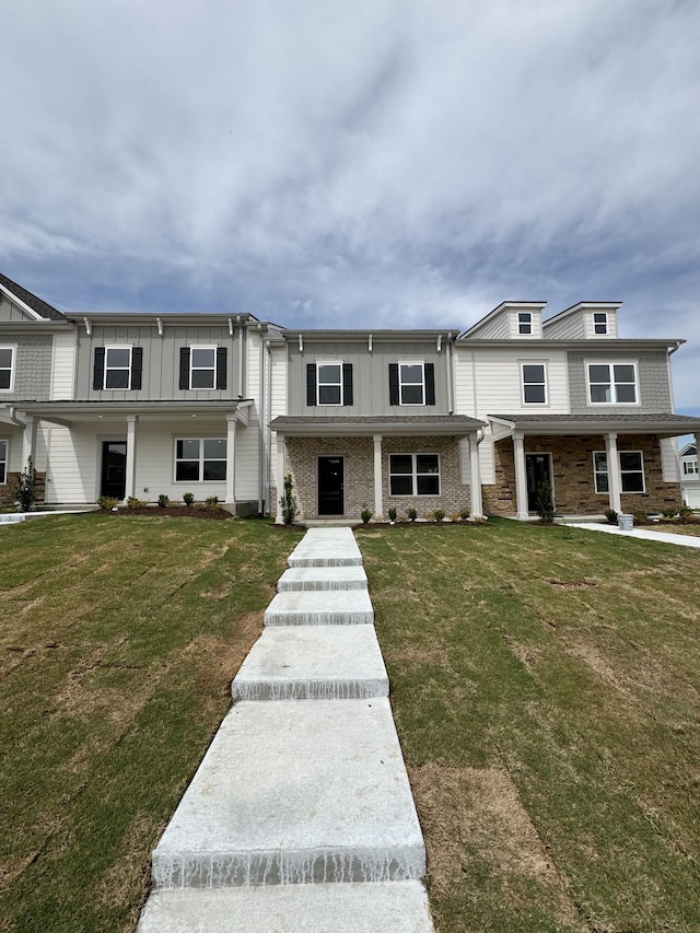 multi unit property featuring board and batten siding and a front yard