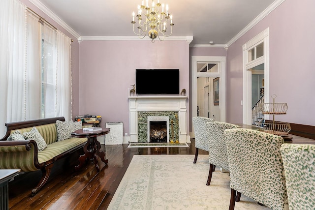 living area with crown molding, a notable chandelier, wood finished floors, and a high end fireplace