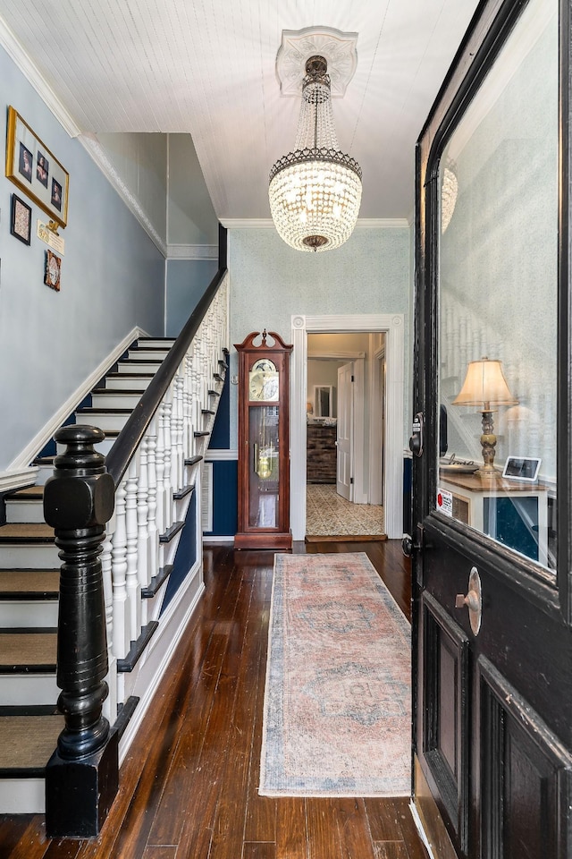 foyer featuring an inviting chandelier, hardwood / wood-style floors, stairs, and crown molding