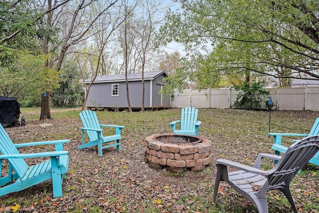 view of yard featuring a fire pit, an outdoor structure, a shed, and fence