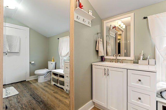 bathroom featuring baseboards, wood finished floors, vanity, and vaulted ceiling