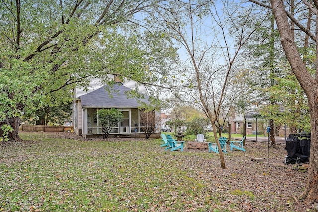 view of yard featuring an outdoor fire pit, fence, and a sunroom