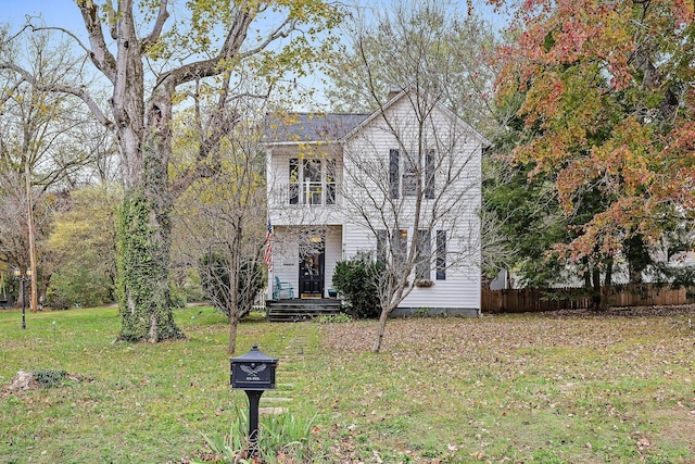 view of front of house featuring a front yard, a balcony, and fence