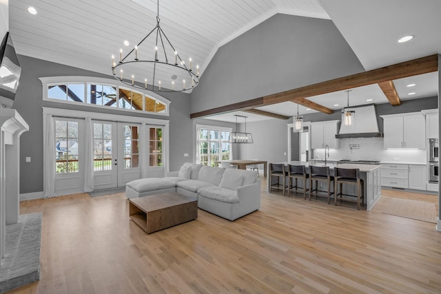 living area with beam ceiling, a notable chandelier, light wood-style flooring, and high vaulted ceiling