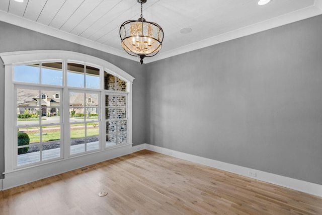 unfurnished room with a chandelier, wood finished floors, a wealth of natural light, and ornamental molding