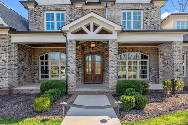 view of exterior entry featuring french doors and brick siding