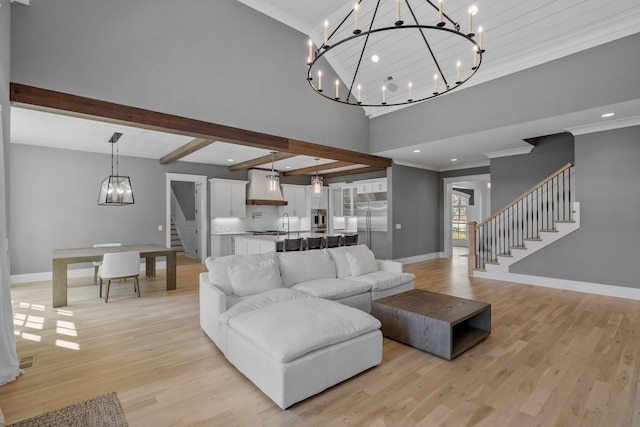 living room with light wood-type flooring, baseboards, a notable chandelier, and stairs