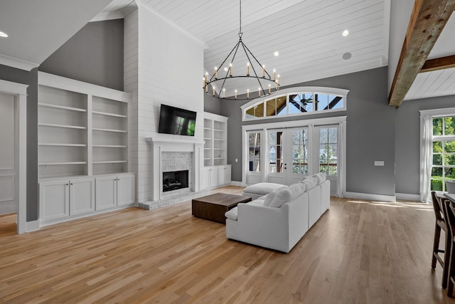 living room with a brick fireplace, a notable chandelier, wood finished floors, and high vaulted ceiling