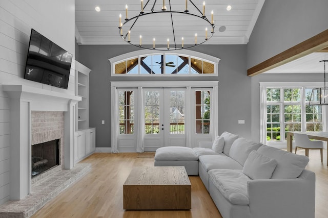 living room featuring a wealth of natural light, wood finished floors, high vaulted ceiling, and a chandelier