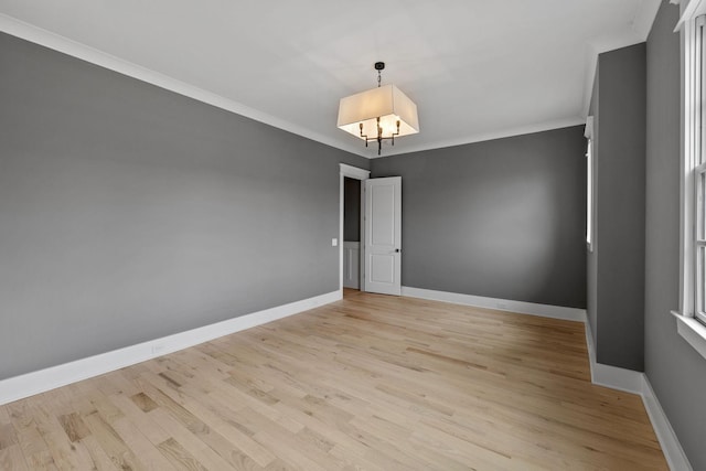 unfurnished room with a chandelier, light wood-style flooring, crown molding, and baseboards