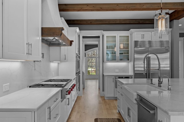 kitchen featuring custom exhaust hood, beamed ceiling, appliances with stainless steel finishes, and white cabinetry