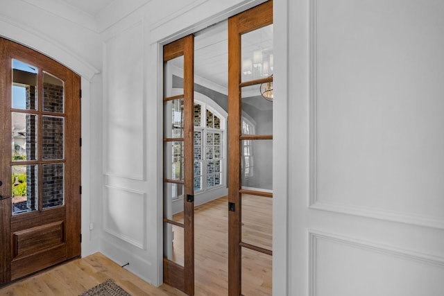 entrance foyer with a wealth of natural light, crown molding, and light wood-type flooring