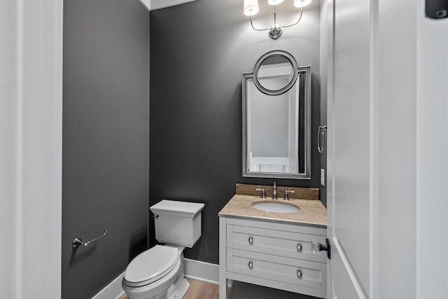 bathroom with baseboards, toilet, wood finished floors, and vanity