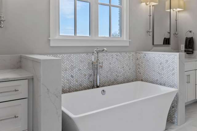 full bathroom with a soaking tub, marble finish floor, and vanity