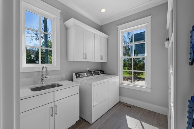 laundry room with visible vents, baseboards, washer and dryer, cabinet space, and a sink