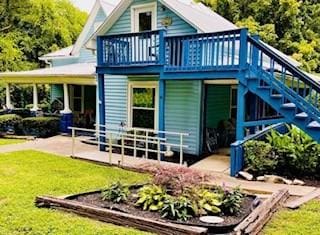 back of property with a lawn, a vegetable garden, and stairs