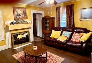 living area featuring a fireplace, wood finished floors, a ceiling fan, and crown molding