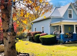 view of property exterior with a porch and a yard