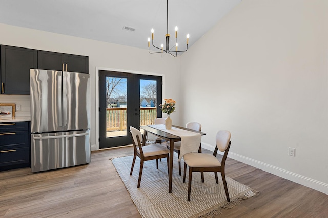 dining room with light wood-style flooring, french doors, baseboards, and an inviting chandelier