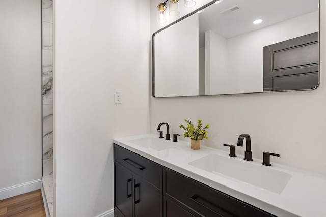 full bathroom featuring double vanity, visible vents, wood finished floors, and a sink