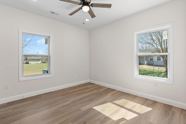 spare room featuring light wood-style floors, baseboards, and a wealth of natural light