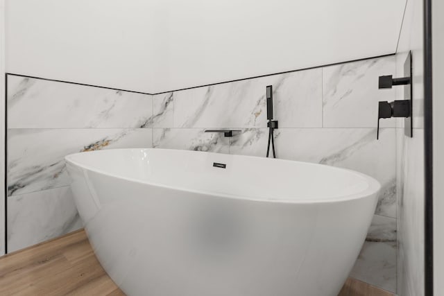 full bathroom featuring a freestanding tub and wood finished floors