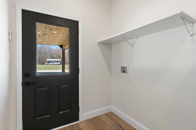 washroom with baseboards, washer hookup, wood finished floors, and laundry area