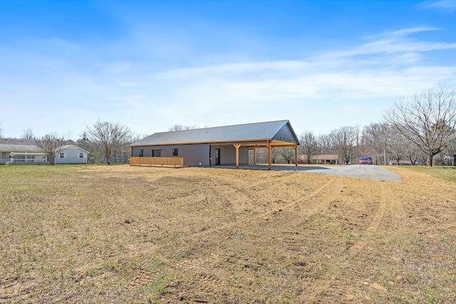 back of property with an attached carport, driveway, and metal roof