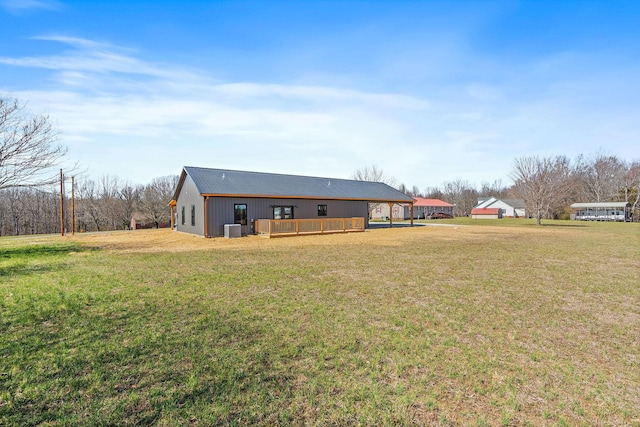 rear view of house with a deck, an attached carport, central air condition unit, and a yard